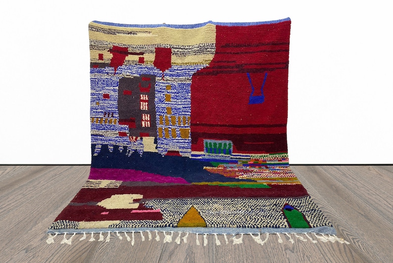 May include: A colorful abstract rug with geometric patterns in shades of red, blue, green, yellow, and white. The rug has a fringe border.