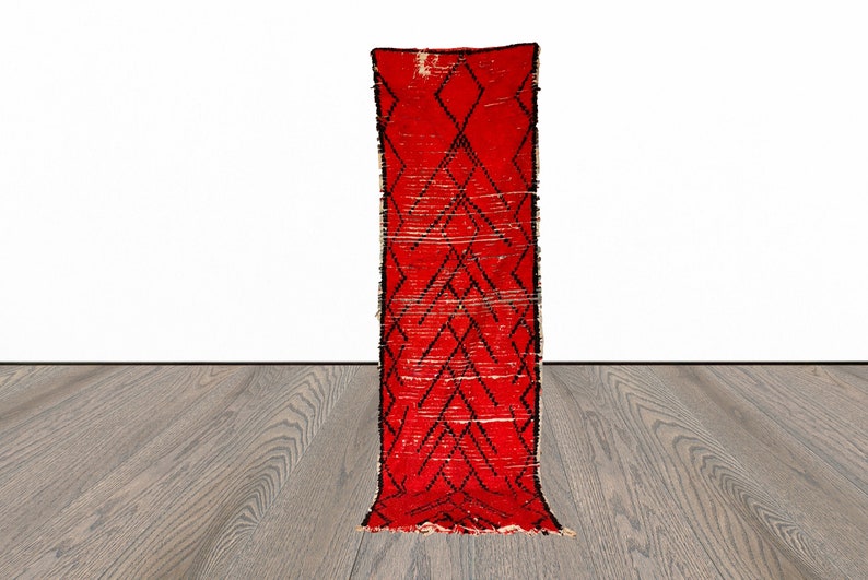 Op de afbeelding: Een rood en zwart loperkleed met een ruitpatroon. Het kleed is gemaakt van wol en heeft een handgeweven textuur.