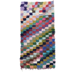 May include: A colourful, rectangular rug with a checkered pattern in shades of pink, blue, green, red, and yellow.