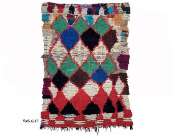 May include: A colorful Moroccan rug with a diamond pattern in shades of red, green, blue, black, and white. The rug is approximately 5 feet by 6.6 feet.