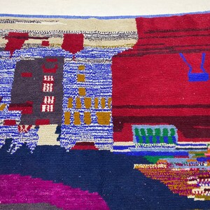 May include: A colorful abstract rug with geometric shapes and patterns in shades of blue, red, green, yellow, and white. The rug has a textured woven design.