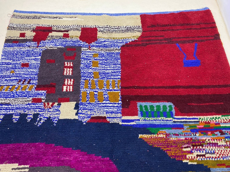 May include: A colorful abstract rug with geometric shapes and patterns in shades of blue, red, green, yellow, and white. The rug has a textured woven design.
