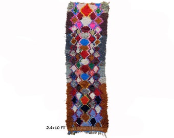 May include: A long, narrow, colorful Moroccan rug with a geometric pattern. The rug is made of wool and has a fringe on the ends. It measures 2.4 x 10 feet.