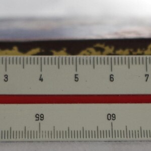 May include: A close-up of a brown wooden box with gold trim. The box is about 9 inches long and is sitting on a ruler.