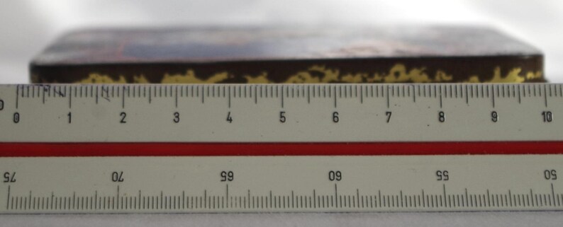 May include: A close-up of a brown wooden box with gold trim. The box is about 9 inches long and is sitting on a ruler.