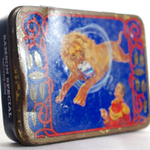 May include: Vintage tin box with a blue background featuring a lion performing a circus act. The text "SAMSON SPECIAL half-ware shag" is printed on the side of the box.