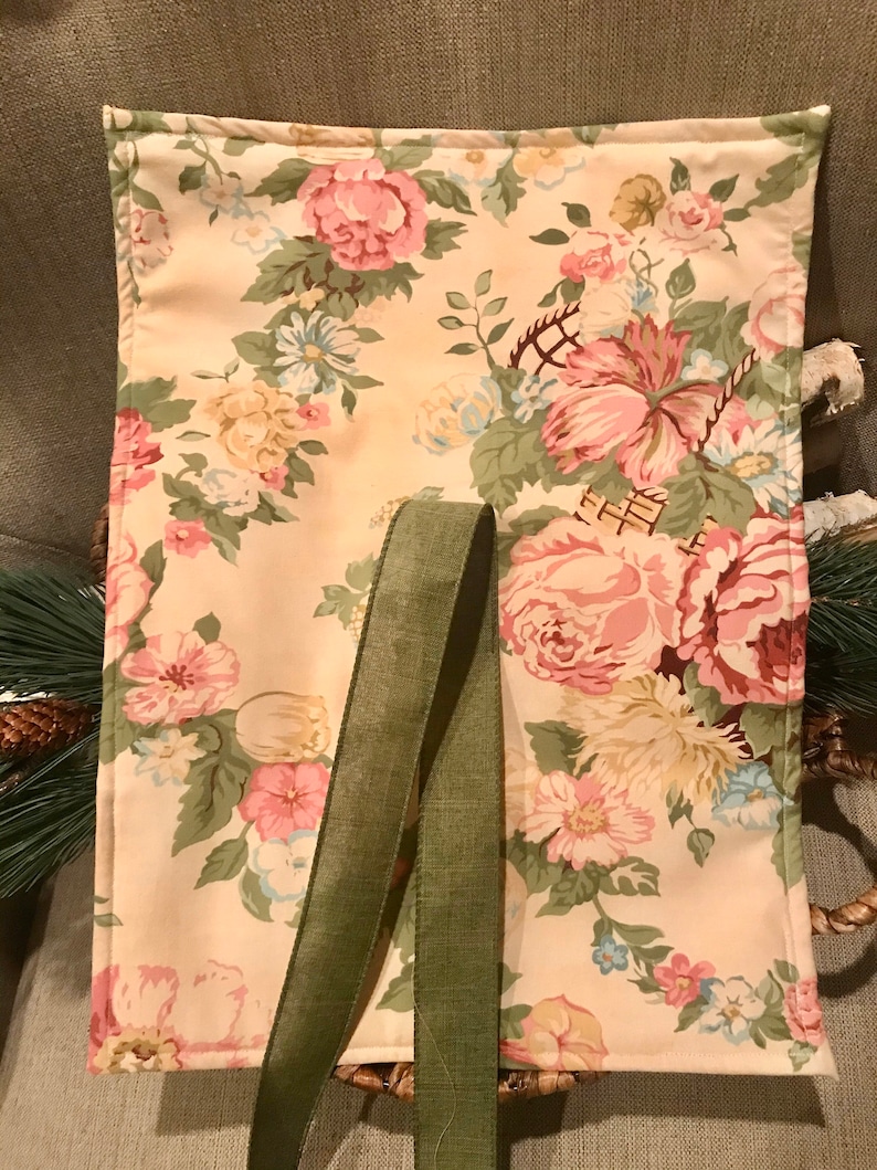 May include: A beige fabric tote bag with a floral print and green fabric straps. The bag is lined with a cream fabric and has a floral print.