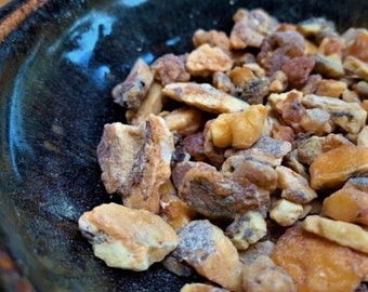 May include: A close-up of a bowl filled with light brown resin pieces. The resin is irregularly shaped and has a slightly powdery texture.