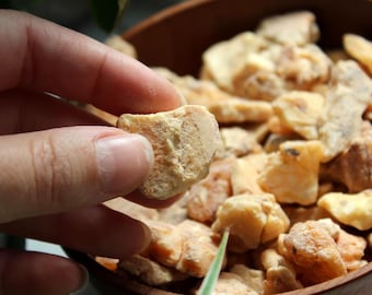 May include: A collection of irregular, light tan and beige resinous chunks with a matte, textured surface. The pieces are varied in size and shape, displaying a natural, earthy appearance with subtle variations in color ranging from pale yellow to brown.