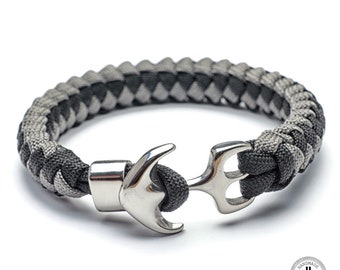 May include: A black and gray braided paracord bracelet with a silver anchor clasp. The bracelet is handmade and features a "CordDraid" logo.