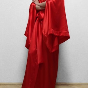 May include: A long, red satin robe with wide sleeves and a sash tie. The robe is floor-length and has a V-neckline.