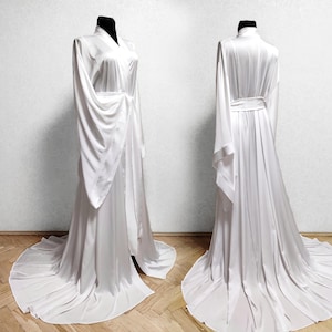 May include: A white satin robe with long sleeves and a tie belt. The robe has a flowing, elegant design.