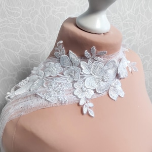 Op de afbeelding: Witte kantversiering met bloemmotieven en parel accenten. De versiering is delicaat en ingewikkeld, perfect om een ​​toets van elegantie toe te voegen aan elk project.