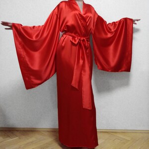 May include: A long, red satin robe with wide sleeves and a sash tie. The robe is made of a soft, luxurious fabric and has a classic kimono style.