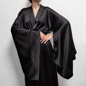 May include: A black satin robe with long, wide sleeves and a wrap closure. The robe is made of a soft, luxurious fabric and has a relaxed fit.