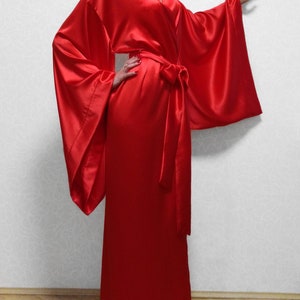 May include: A long, red satin robe with wide sleeves and a sash tie. The robe is floor-length and has a classic kimono style.