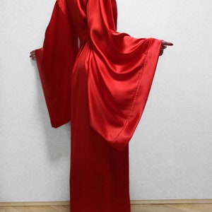 May include: A long, red satin robe with wide sleeves. The robe is tied at the waist with a sash.