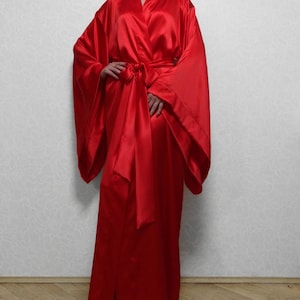 May include: A long, red satin robe with wide sleeves and a sash tie. The robe is floor-length and has a classic kimono style.