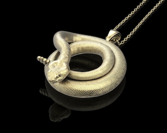 May include: A gold-colored snake pendant necklace. The snake is coiled in a circle and has a detailed texture. The necklace is made of a delicate chain.