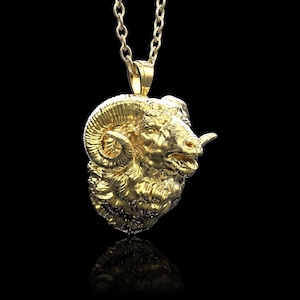 Könnte beinhalten: Eine goldfarbene Halskette mit einem Anhänger, der eine detaillierte, realistische Skulptur eines Widderkopfes mit gekräuselten Hörnern zeigt.