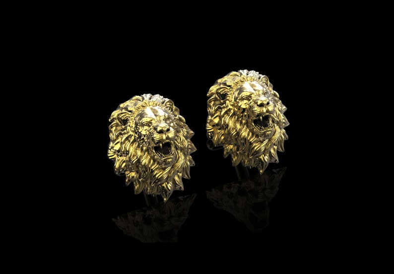 May include: A pair of gold lion head cufflinks. The lion heads are facing forward with their mouths open and their teeth showing.