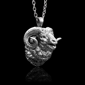 Könnte beinhalten: Eine silberne Halskette mit einem detaillierten Widderkopf mit gekräuselten Hörnern.
