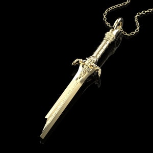 May include: A gold-coloured sword pendant necklace. The sword has intricate details and a chain attached to the top.