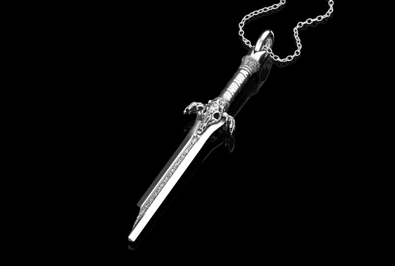K&ouml;nnte beinhalten: Eine silberne Schwertpendantkette mit einem detaillierten Design. Das Schwert hat eine spitze Spitze und einen dekorativen Griff. Die Kette ist an einer silbernen Kette.