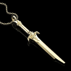 May include: A gold-coloured sword pendant necklace. The sword has intricate details and a pointed tip. The chain is made of small, linked circles.