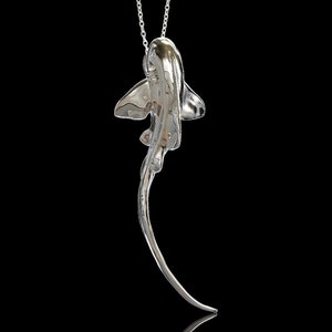 May include: A silver necklace with a detailed, three-dimensional pendant shaped like a stingray. The pendant is suspended from a delicate silver chain.