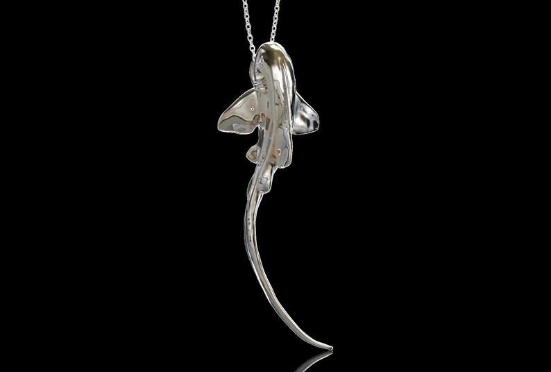 May include: A silver necklace with a detailed, three-dimensional pendant shaped like a stingray. The pendant is suspended from a delicate silver chain.