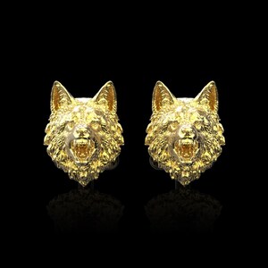 Op de afbeelding: Een paar gouden wolfskop oorknopjes. De bek van de wolf is open en zijn tanden zijn zichtbaar.