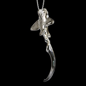May include: A silver shark pendant necklace with a single diamond on the shark's head.