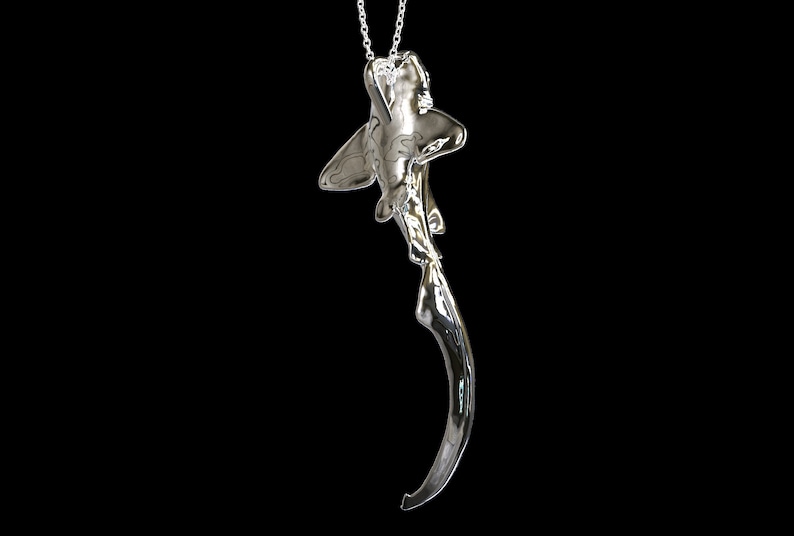 May include: A silver shark pendant necklace with a single diamond on the shark's head.