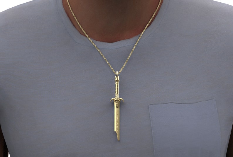 May include: A gold chain necklace with a sword pendant. The sword is detailed with intricate carvings and has a pointed tip.