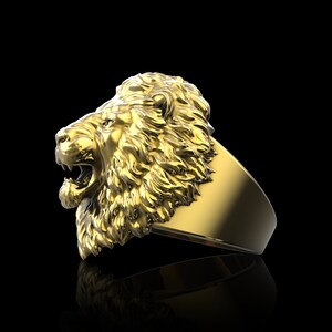 Puede incluir: Un anillo de oro con un dise&ntilde;o detallado de cabeza de le&oacute;n. La boca del le&oacute;n est&aacute; abierta y su melena est&aacute; esculpida con detalles intrincados.