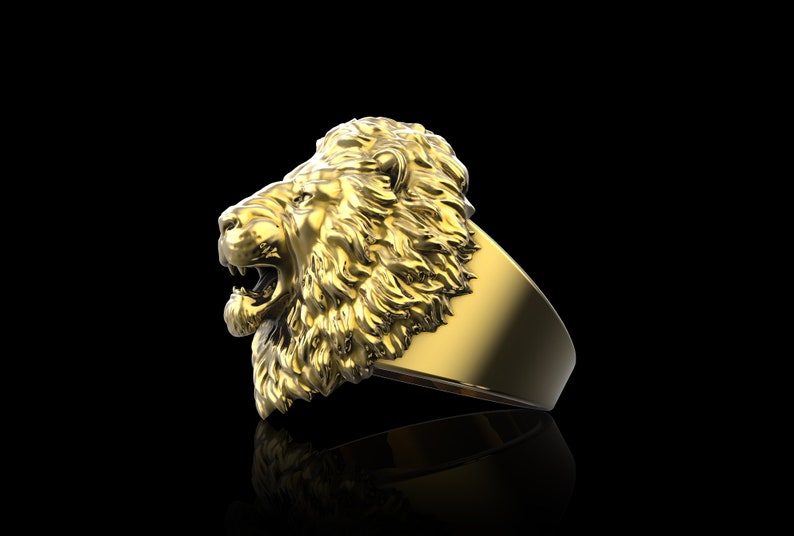 Puede incluir: Un anillo de oro con un dise&ntilde;o detallado de cabeza de le&oacute;n. La boca del le&oacute;n est&aacute; abierta y su melena est&aacute; esculpida con detalles intrincados.