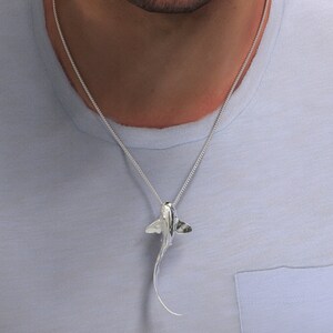 May include: A silver chain necklace with a silver pendant shaped like a stingray.