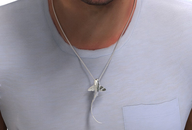 May include: A silver chain necklace with a silver pendant shaped like a stingray.