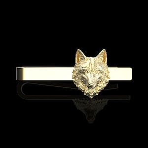 Pode incluir: Um prendedor de gravata dourado com um design de cabeça de lobo. A cabeça de lobo é detalhada e realista, com um padrão de pelo texturizado.