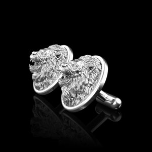 May include: A pair of silver cufflinks with a detailed lion head design. The lion heads are facing forward with their mouths open.