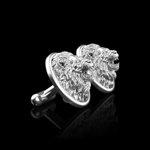 May include: A pair of silver cufflinks featuring detailed lion head designs. The lion heads are facing forward with their mouths open.