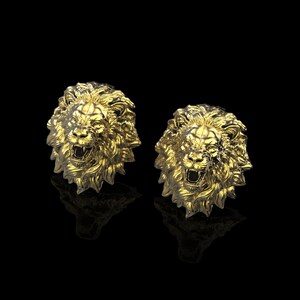 May include: A pair of gold lion head cufflinks. The lion heads are detailed and have a roaring expression.