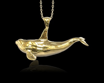 May include: A gold-colored pendant necklace featuring a detailed orca whale design. The pendant is suspended from a delicate gold chain.