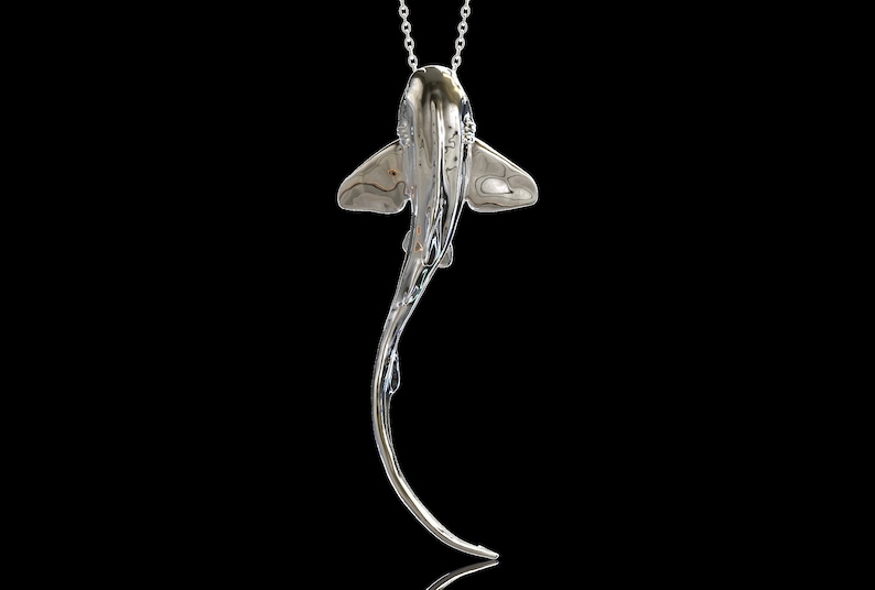 May include: A silver-toned pendant necklace featuring a detailed, stylized stingray design. The pendant hangs from a delicate silver chain.