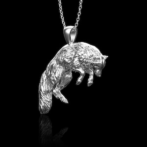 Op de afbeelding: Een zilveren vos-hangerketting. De vos is afgebeeld in een springende pose met zijn staart om zijn lichaam gekruld.