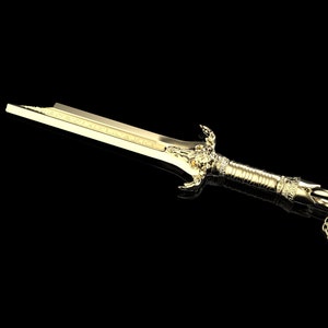 May include: A gold sword pendant necklace with a detailed design and a chain.