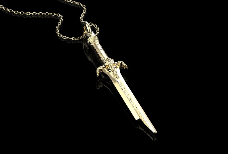 May include: A gold-coloured sword pendant necklace with a detailed design. The sword has a pointed tip and a decorative handle.