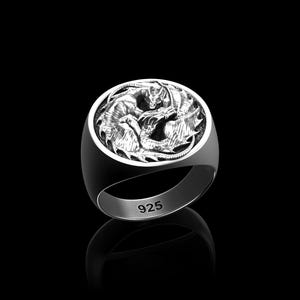 May include: A silver ring with a detailed dragon design. The ring features a round face with two dragons in a fighting pose. The band is smooth and the ring is marked with "925". The ring is set against a black background.