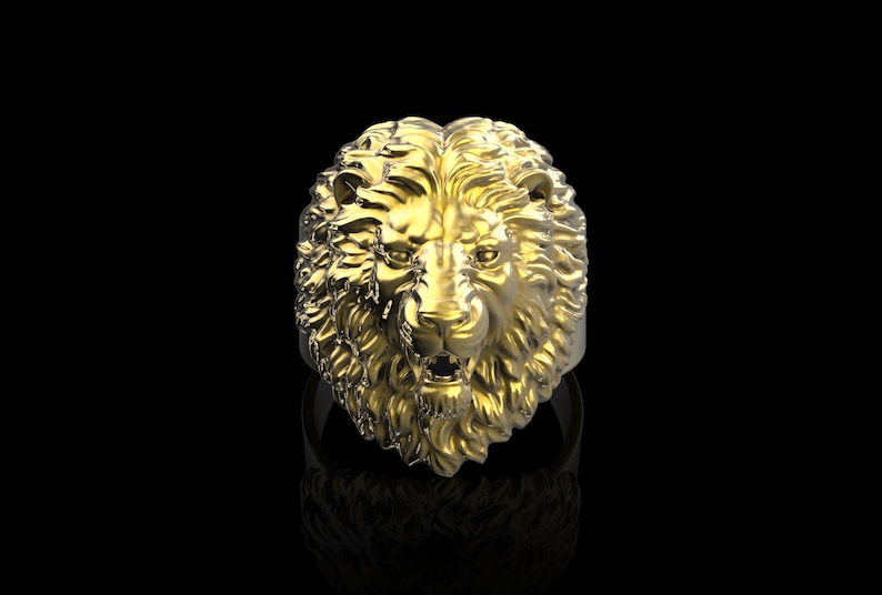 Puede incluir: Un anillo de cabeza de le&oacute;n de oro con un dise&ntilde;o detallado. La melena del le&oacute;n est&aacute; esculpida de forma intrincada y el anillo est&aacute; sobre un fondo negro.